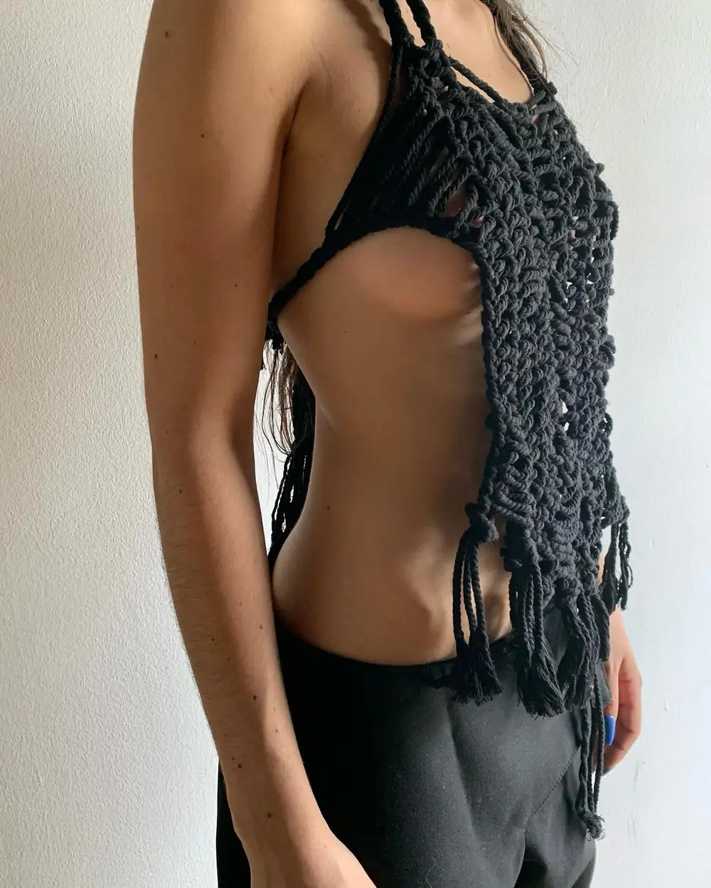 Modelo con un top artesanal de macramé negro y pantalón oscuro, en un estilismo vanguardista.